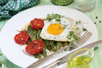 Scrambled eggs with green beans, tomatoes with white wine on a green, wooden background