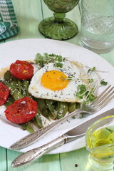 Scrambled eggs with green beans, tomatoes with white wine on a green, wooden background