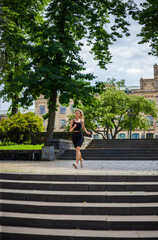 A young blonde woman with a sporty physique in a black T-shirt and in black tight sports shorts runs up the stairs