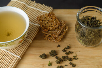Cup with green herbal tea and dried ivan tea leaves on the table