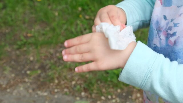 The child wipes his hands with a wet napkin.  disinfecting hands with a wet wipe