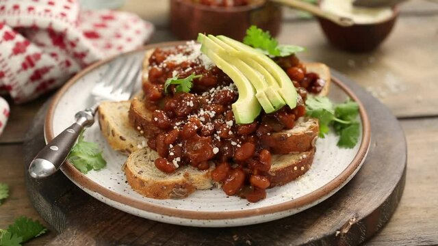 Baked beans on toast with cheese and cilantro, adding avocado on top of the sandwich, recipe process video