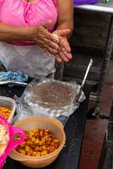 woman's hands making a tortilla in a traditional way to do other typical dishes