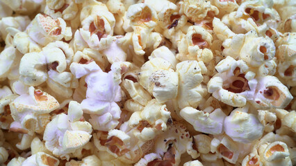 Heap of delicious popcorn. Scattered popcorn texture background. Selective focus. Salt popcorn on the wooden table.