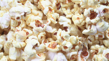 Heap of delicious popcorn. Scattered popcorn texture background. Selective focus. Salt popcorn on the wooden table.