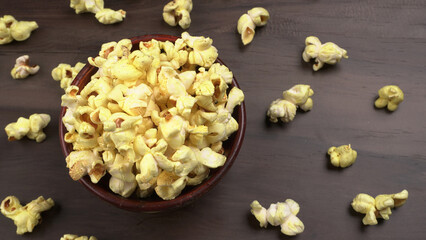 Heap of delicious popcorn. Scattered popcorn texture background. Selective focus. Salt popcorn on the wooden table.