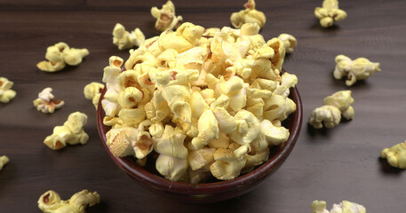 Heap of delicious popcorn. Scattered popcorn texture background. Selective focus. Salt popcorn on the wooden table.