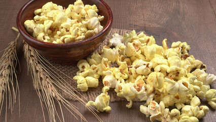 Heap of delicious popcorn. Scattered popcorn texture background. Selective focus. Salt popcorn on the wooden table.