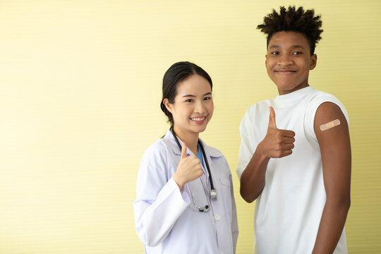 portrait asian woman doctor and black man show thumb up or good sign after injection vaccine . vaccinated against coronavirus in hospital
