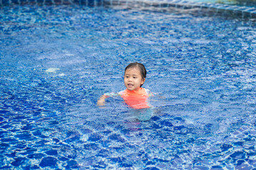 Fototapeta na wymiar Little Adorable Asian girl have fun at outdoor swimming pool. Summer background.