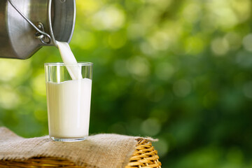 milk pouring from metal can into glass