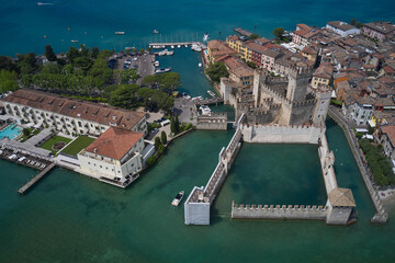 Top view of the 13th century castle. Aerial view of Sirmione Castle, Lake Garda, Italy. Italian castles Scaligero on the water. Flag of Italy on the towers of the castle on Lake Garda.