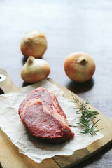 Raw steak on the table
Cooking. Raw piece of steak on the table with piece of rosemary
