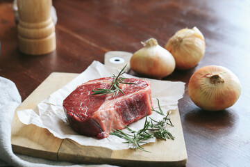 Raw steak on the table
Cooking. Raw piece of steak on the table with piece of rosemary
