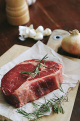 Raw steak on the table
Cooking. Raw piece of steak on the table with piece of rosemary
