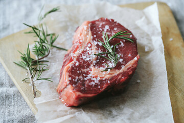 Raw steak on the table
Cooking. Raw piece of steak on the table with piece of rosemary
