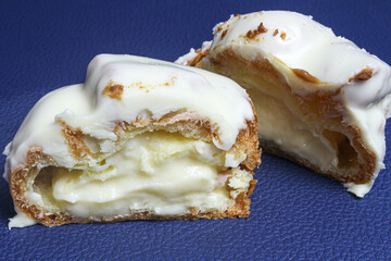 Vanilla choux pastry cake with white chocolate top on blue background.