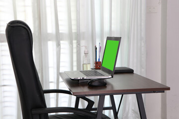 Computer green screen. Communicates internet with customer home. Alcohol, pen, pencil, book on table. Cozy office workplace, remote work, E learning concept. modern laptop at home ( work for Home)	