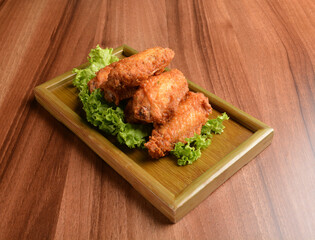 deep fried crispy chicken wings on lettuce and bamboo plate wood table asian snack halal menu fast food cuisine