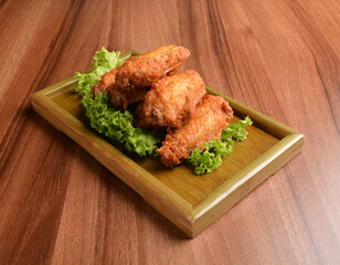 deep fried crispy chicken wings on lettuce and bamboo plate wood table asian snack halal menu fast food cuisine