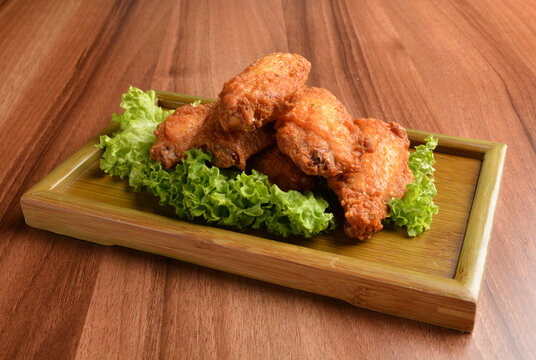 deep fried crispy chicken wings on lettuce and bamboo plate wood table asian snack halal menu fast food cuisine