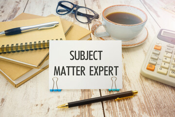 A sign with the inscription SUBJECT MATTER EXPERT on the table with coffee and notebooks