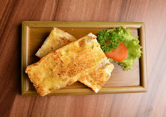 oven baked garlic butter French toast bread on lettuce and bamboo plate wood table pastry halal menu