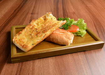 oven baked garlic butter French toast bread on lettuce and bamboo plate wood table pastry halal menu