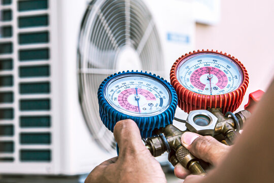 Mechanic Air Repair Using Manifold Gauge For Filling Home Air Conditioner And Checking Maintenance Outdoor Air Compressor Unit.