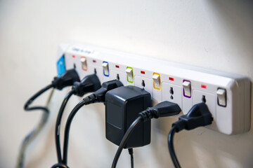 Old and damaged electric adapter power plug has many appliances are plugged outlet socket concept of risk danger overloaded current electrical.