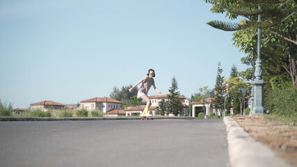 attractive fashionable asian woman skater playing surfskate on neighborhood street with fast speed like professional. female surf skating around neighbor. balancing skill enjoyment relaxation.