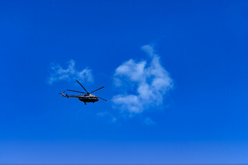 Fototapeta na wymiar Flying helicopter on the background of clouds and blue sky