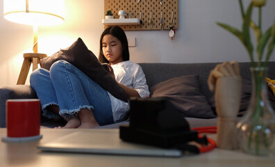 Asian girl sitting on sofa and using digital tablet.