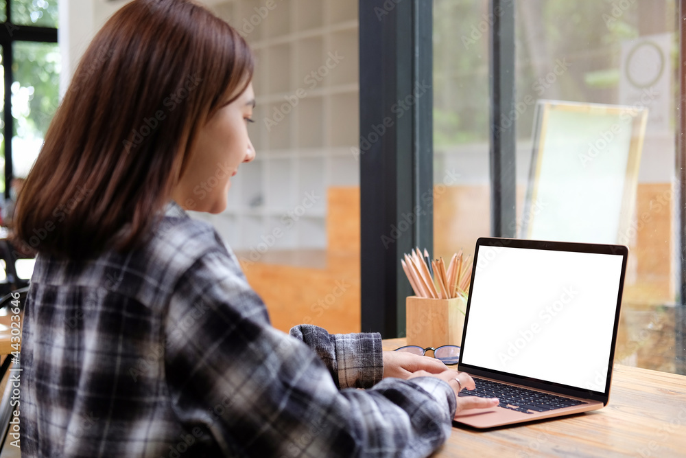 Wall mural young female designer working with laptop in creative office.