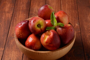 Fototapeta na wymiar Nectarine. Ripe juicy organic nectarines in a wooden bowl. Whole and sliced fruit on a wooden table.