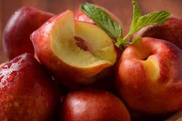 Nectarine. Ripe juicy organic nectarines  in a wooden bowl. Whole and sliced fruit on a wooden table.