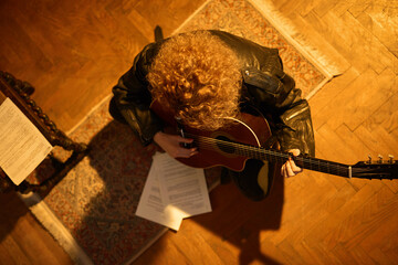 Woman playing acoustic guitar in a retro vintage room.