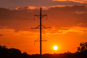 power line pole against the background of the sun at sunset 