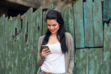 Young cute female using smartphone on the street.