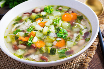 Chicken fillet vegetable soup in  bowl on wooden rustic table.