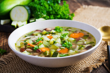 Chicken fillet vegetable soup in  bowl on wooden rustic table.