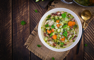 Chicken fillet vegetable soup in  bowl on wooden rustic table. Top view, flat lay