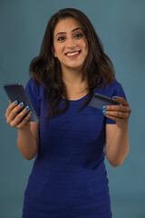 Portrait of a young woman holding a mobile and a credit card.