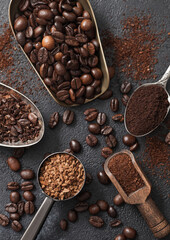 Ground and bean coffee and freeze dried instant coffee granules in various spoons and scoops on black background.