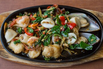 Thai Cuisine, Spicy Stir Fried Seafood serving on hot plate with selective focus