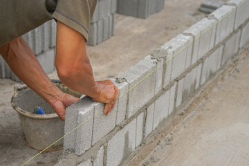 industrial bricklayer installing brick blocks on construction site, selective focus