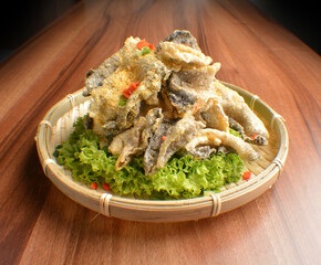 deep fried crispy fish skin with salted egg yolk in bamboo basket on wood table asian snack halal menu