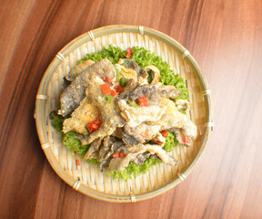 deep fried crispy fish skin with salted egg yolk in bamboo basket on wood table asian snack halal menu