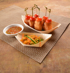 deep fried shrimp paste roll (wu Xiang) with achar and spicy sauce in bento box on wood table asian snack halal menu