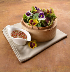 beautiful flower vegetables salad in bamboo basket with homemade salad dressing sauce on wood table asian vegan halal menu